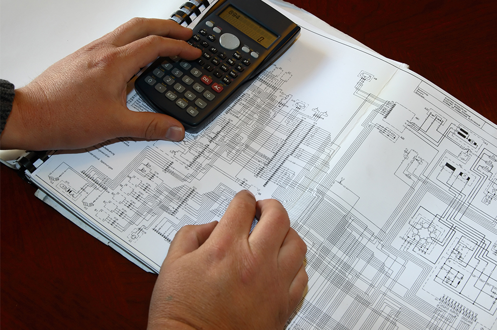 Person reviewing electrical drawings with calculator